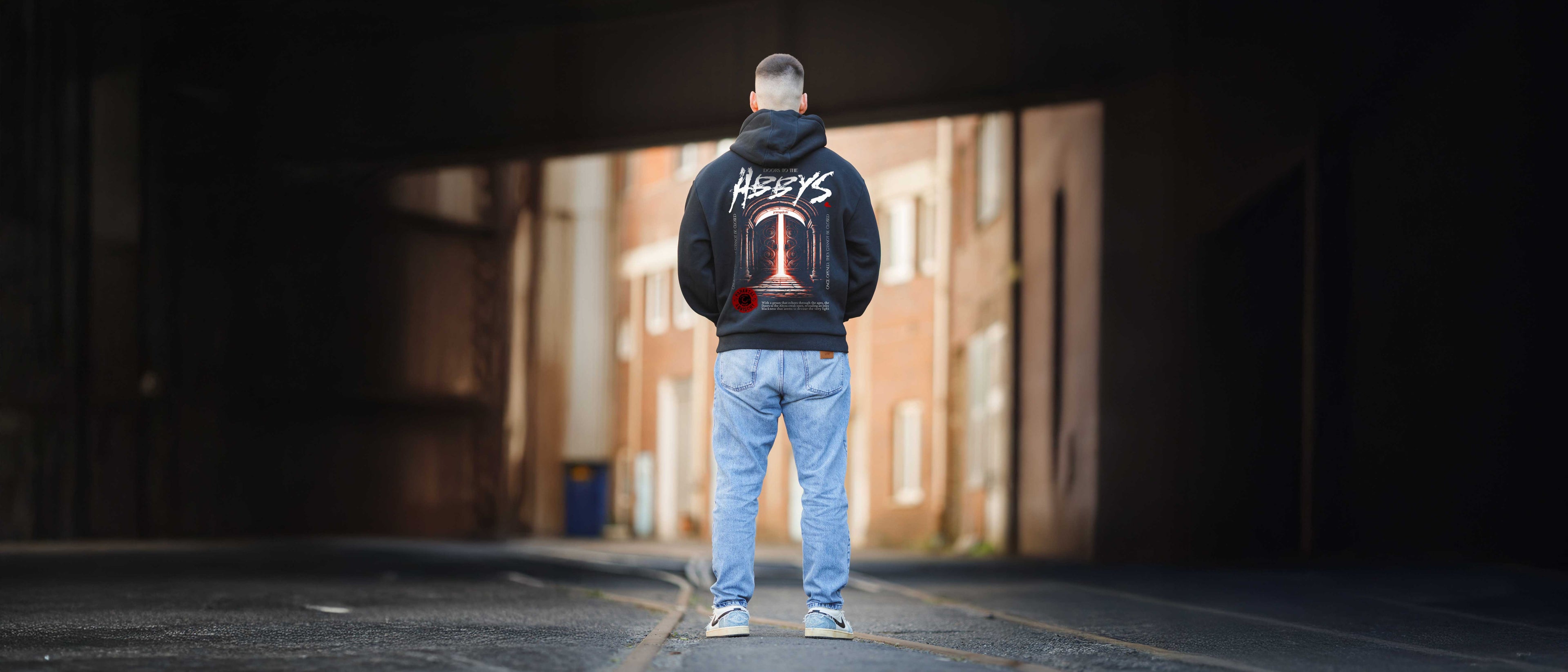 Ein Mann ist von hinten zu sehen, mit einem schwarzen Hoodie im Abbys Design. 